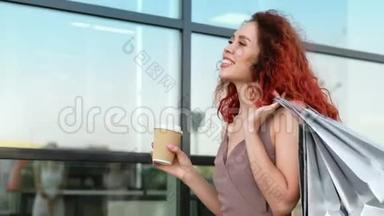 微笑的买家女人，挥舞着头发，走在玻璃商场的窗前